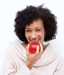 woman with dental implants in Salt Lake City biting into a red apple 