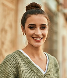 a person smiling and standing on a sidewalk in a city
