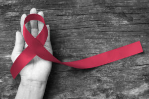 Person holding a red ribbon for oral cancer