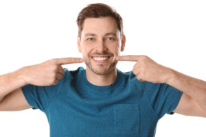 Smiling man pointing at beautiful teeth