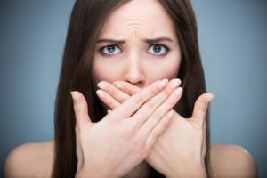 woman with bad breath covering mouth